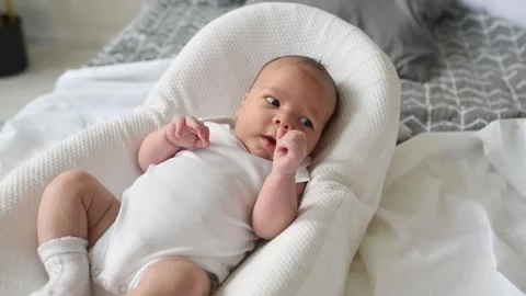 A newborn boy lies on a large bed of parents in the bedroom at home Video stock 141661693