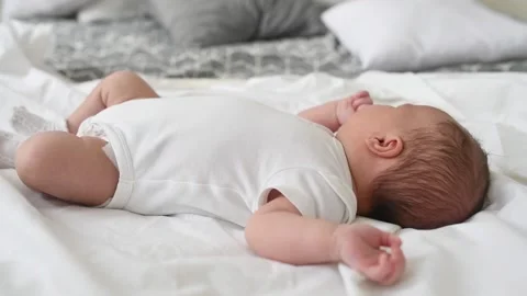 A newborn boy lies on a large bed of parents in the bedroom at home Stock Footage 141661698