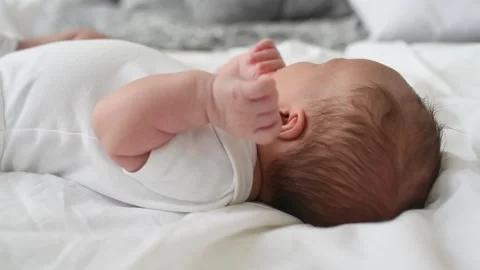 A newborn boy lies on a large bed of parents in the bedroom at home Stock Footage 141661701