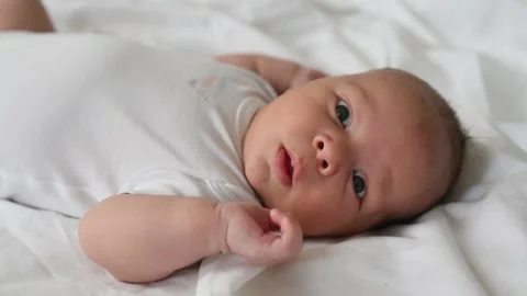 A newborn boy lies on a large bed of parents in the bedroom at home Video stock 141661702