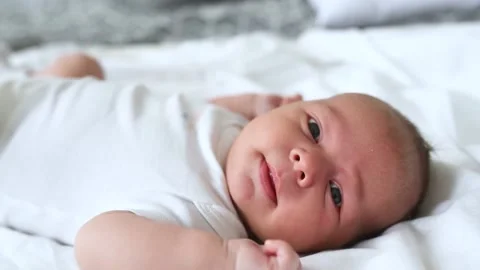 A newborn boy lies on a large bed of parents in the bedroom at home Video stock 141661705