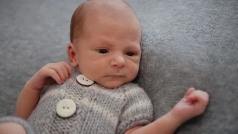A newborn in clothes on a gray background. The first days of life Stock Footage 132602521