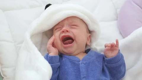 Newborn crying baby boy. New born child tired and hungry in bed under a blue Stock Footage