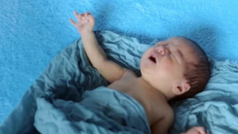 Newborn crying baby boy. New born child tired and hungry in bed under blue Stock Footage