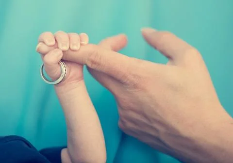 Newborn holding wedding ring. Stock Photos