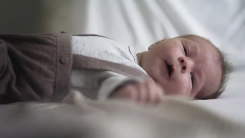 Newborn infant peacefully lying on bed at home during daytime Stock Footage 310250764