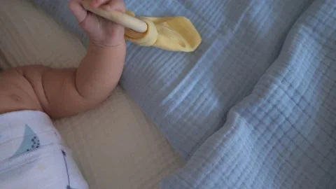 Newborn moving tiny hand with yellow wooden eco toy on a pastel blue blanket Stock Footage 166554870