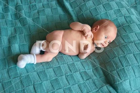 Newborn naked child with widely opened eyes. Stock Photos