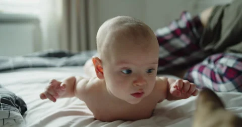 Newborn trying to hold his head and hands up lying on a bed looking at camera Stock Footage 305485667