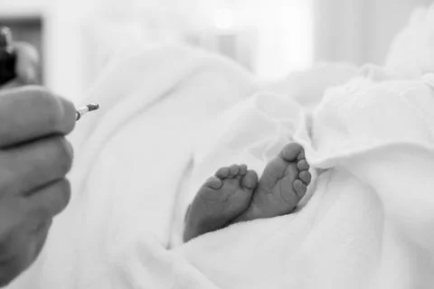 Newborn's Tiny Feet Wrapped in Soft White Blanket Stock Photos
