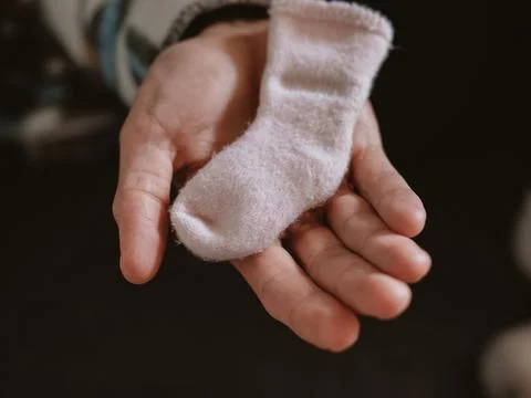 Newborn's Tiny Pink Sock Cradled in Gentle Hands Foto stock
