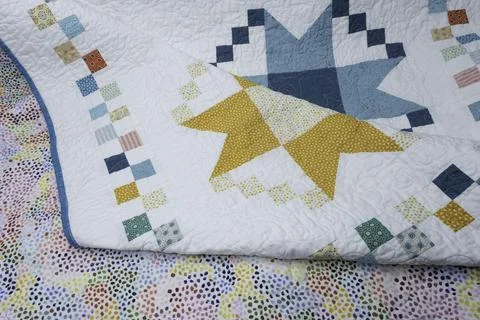 A newly completed quilt, multi colored with a pattern of different colored .. Stock Photos