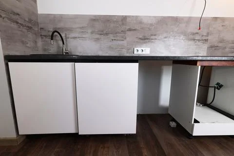 A newly installed kitchen countertop features a black sink and white cabinetr Fotos Stock