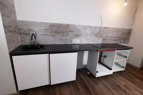 A newly installed kitchen countertop features a black sink and white cabinetr 스톡 사진