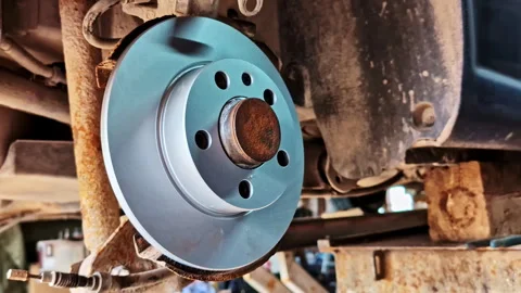 Newly installed rear brake disc on vehicle during repair work showing clean Stock Footage 310212010