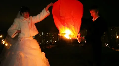 Newly-married couple sets fire to heavenly small lamp in city Vídeos de archivo 10808790