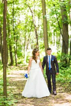 Newly married couple walk on park paths holding hands Foto stock