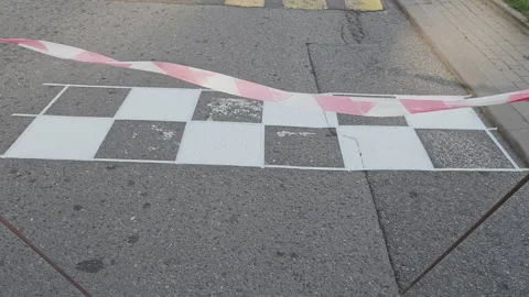 Newly painted black and white checkered finish line on an asphalt road. A red Stock Footage 343962697