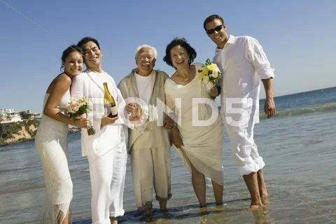 Newlywed Couple With Wedding Guests Celebrating On Beach