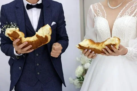 Newlyweds break bread in half. Wedding celebration traditions. Stock Photos