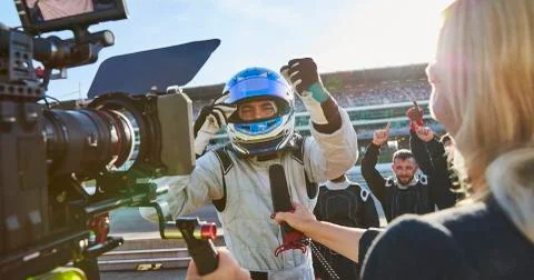 News reporter and cameraman interviewing formula one driver cheering, Stock Photos