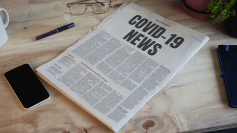 Newspaper falling desk front page title COVID-19 news Stock Footage 126384755
