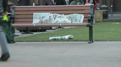 Newspaper left on a city bench blows in the wind. Stock Footage 1086335