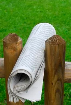 Newspaper rolled between two fenceposts Stock Photos