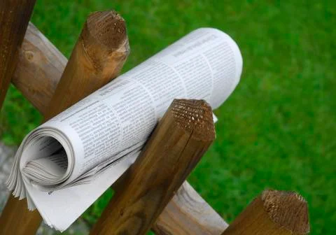 Newspaper rolled between two fenceposts Stock Photos