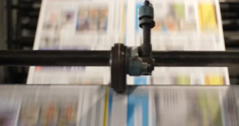 Newspaper runs through a roll machine parallel to the camera view with two Stock Footage 155786107