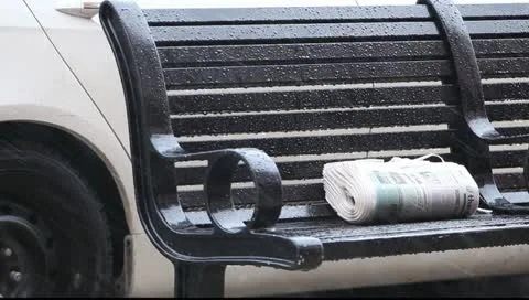 Newspaper on the street bench , rain Stock Footage 10763286