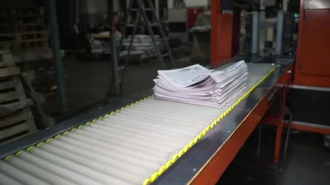 Newspapers fall into large pile and move along the conveyor line. Printing house Stock Footage 171444295