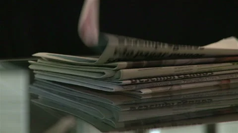 Newspapers falling into a glass table Stock Footage 62559613