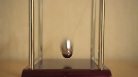 Newton's desk cradle on the table is moving. Balls beat by inertia Stock Footage 141384225