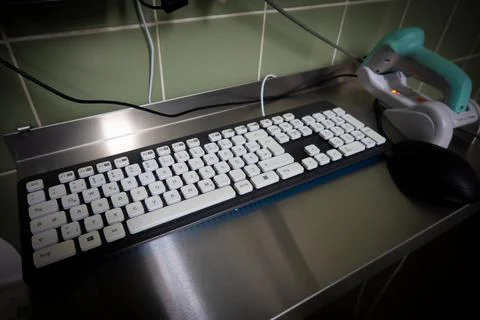 Next to a black computer keyboard is a green barcode scanner Stock-Fotos