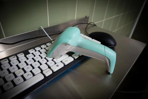 Next to a black computer keyboard is a green barcode scanner 스톡 사진