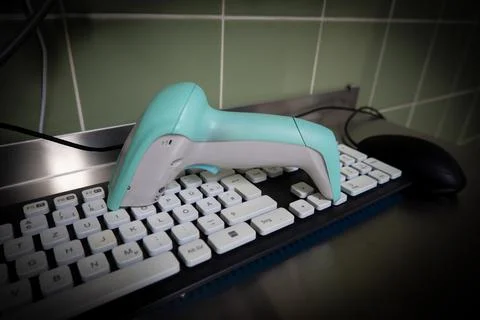 Next to a black computer keyboard is a green barcode scanner Stock Photos