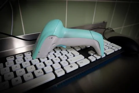 Next to a black computer keyboard is a green barcode scanner Stock-Fotos