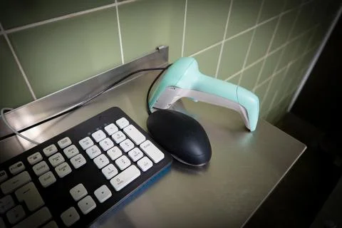 Next to a black computer keyboard is a green barcode scanner 스톡 사진