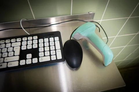 Next to a black computer keyboard is a green barcode scanner 写真素材