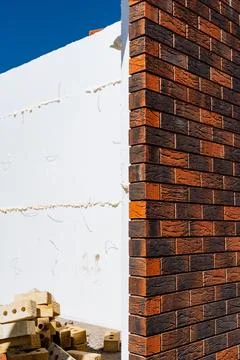 Next to a pile of bricks, a brick wall is under construction. The materials.. Foto stock