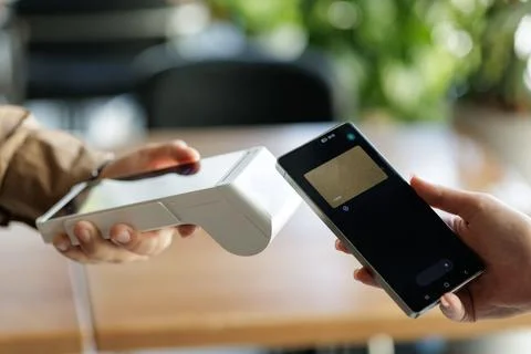 NFC payment with smartphone at wireless terminal in cafe Stock Photos