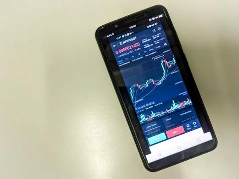 NFT graph in a smartphone screen on a table. Stock Photos