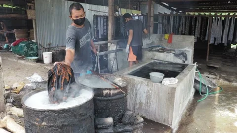 Nglorod batik process to dissolves the wax from the batik cloth Stock Footage 143812414