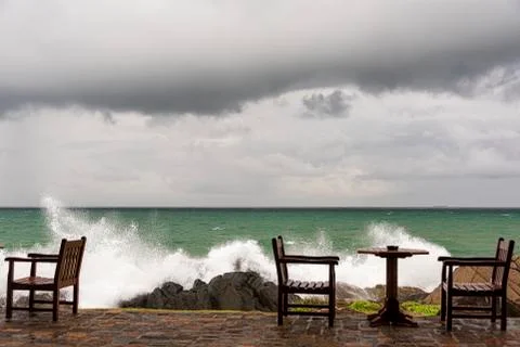Ngry waves crash over rocks on the coast near abandoned tables Stock Photos