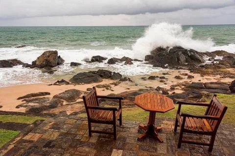 Ngry waves crash over rocks on the coast near abandoned tables Stock Photos