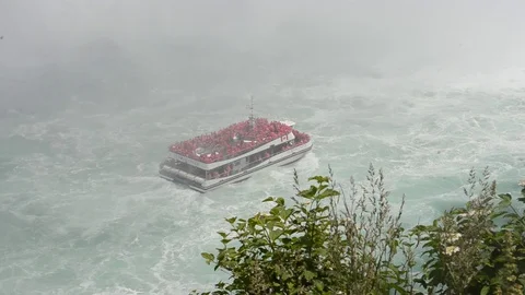 NIAGARA FALLS/CANADA - SEPTEMBER 30, 2019:  Tourist ship under Niagara Falls Stock Footage 128547376