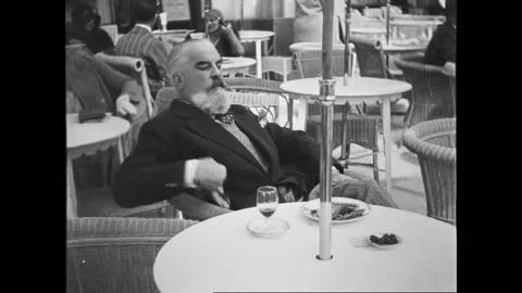 NICE - 1930 - Café patrons sit outside at sidewalk tables as pedestrians walk Stock Footage 304351329