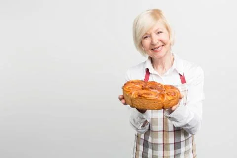 Nice and awesome picture of smiling grandma that baked a tasty pie. She holds Stock Photos
