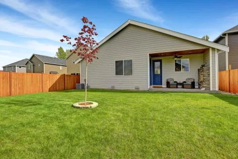 Nice back yard with well kept lawn and view of covered porch with  armchairs  Stock Photos